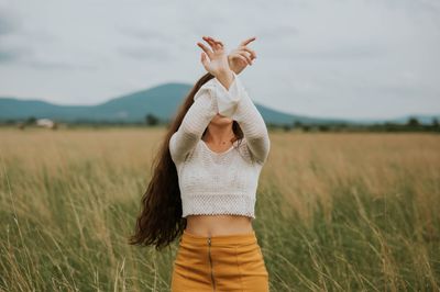 young woman in field with her arms crossed covering her face